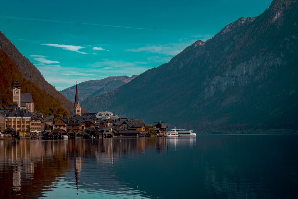 Picturesque shot of Hallstatt waterfront, reflecting town, mountains, and clear blue sky.